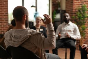 Man sharing his recovery journey during group therapy at a rehab for men in Nashville through Nashville Wellness.